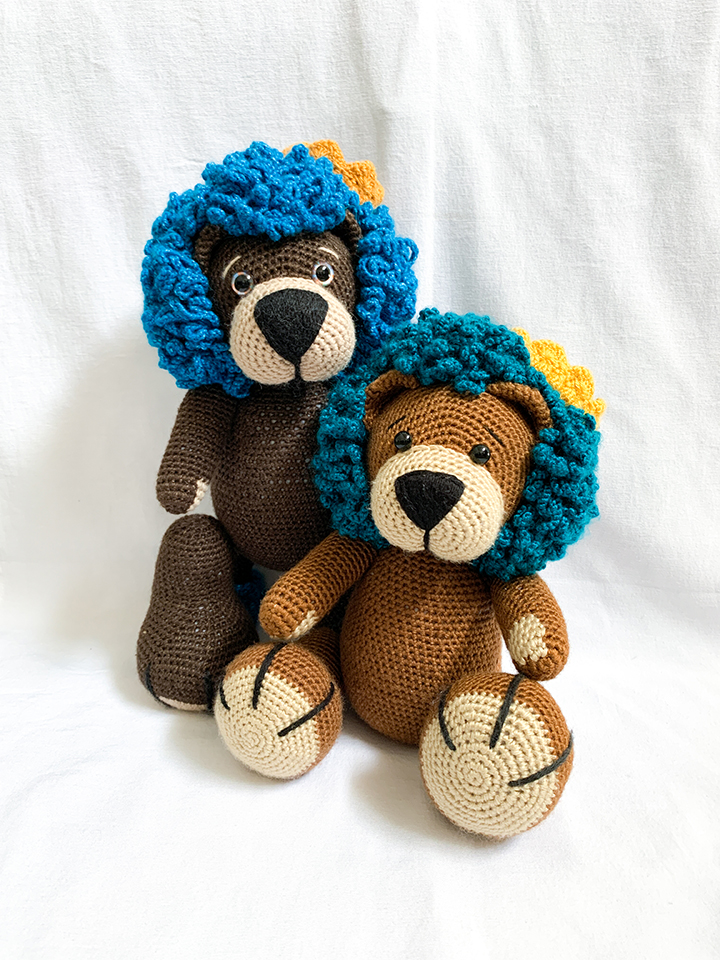 Two lion crochet amigurumi dolls, one standing, one sitting.