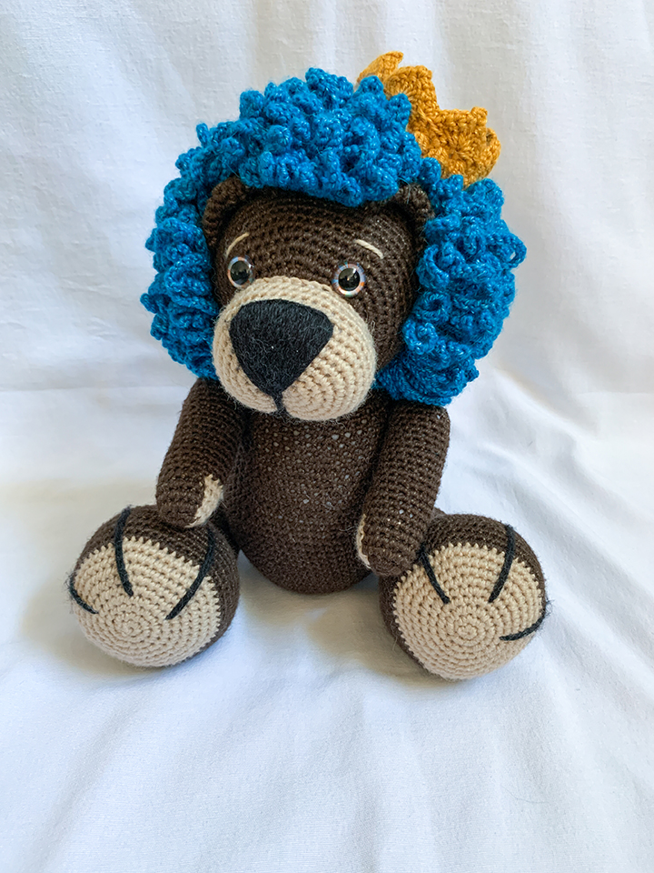 Crochet Amigurumi Lion with blue mane and a crown.
