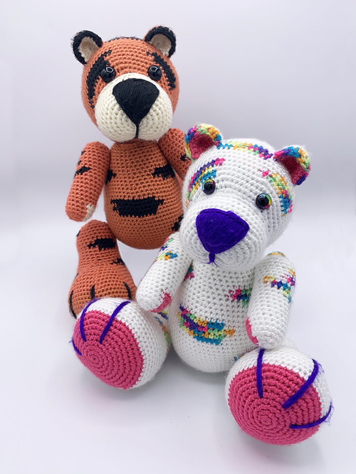 Two Amigurumi Tigers, One orange Tiger, one white with rainbow stripes